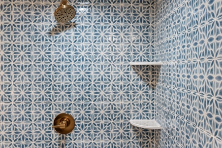 Step into your beautifully tiled shower with stunning geometric patterns and elegant brass fixtures for a refreshing start to your day.