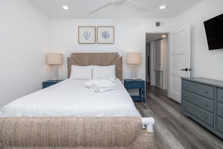 Your queen bedroom can be found downstairs with shiplap walls and a wall-mounted television