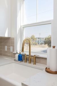 Your bright kitchen features elegant brass fixtures and white marble countertops, perfect for preparing meals while enjoying natural light.