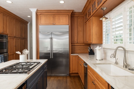 Your fully equipped gourmet kitchen awaits, featuring rich wood cabinetry, marble countertops, professional-grade appliances, and abundant natural light—perfect for preparing memorable meals during your stay.