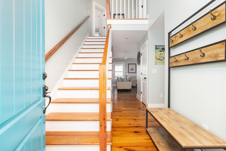 Step inside your charming coastal retreat where warm wood floors and a striking turquoise accent wall create an inviting first impression.