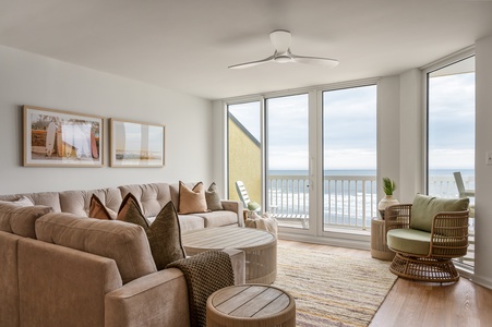 Sink into plush sofas while ocean waves fill your view through floor-to-ceiling windows in this bright, airy living space.