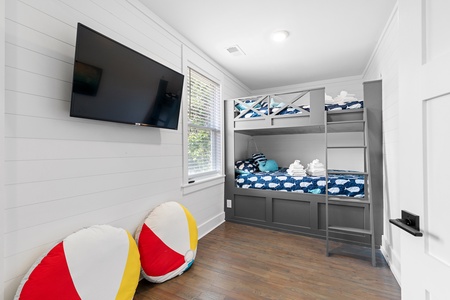 Your kids will love this fun bunk room with built-in beds, wall-mounted TV, and colorful beach ball pillows