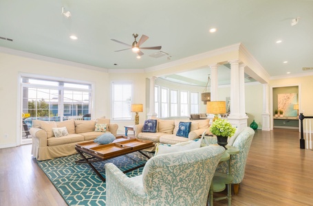 Relax in your spacious living room with coastal-inspired decor, comfortable seating, and bright windows offering pool views.