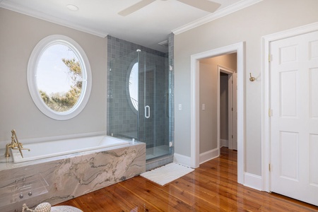 The primary en suite bathroom boasts a glass walk-in shower and a deep soaking tub