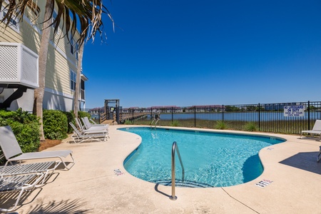 A sparkling waterfront pool with lounge chairs is the perfect place to soak up the sun