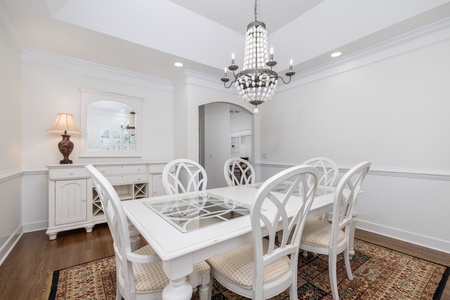 Elegant dining room features beautiful white furnishings, decorative chandelier, and classic details perfect for memorable meals during your stay.