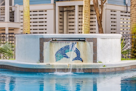 Dive into relaxation with this stunning pool featuring a decorative waterfall and mosaic dolphin design, creating your perfect aquatic escape.