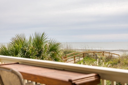 Oceanfront deck with beach boardwalk and scenic coastal dunes.