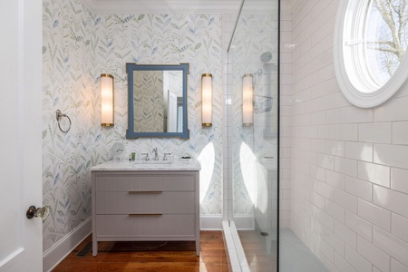 Your king en suite bathroom has coastal wallpaper, single vanity, and a glass walk-in shower