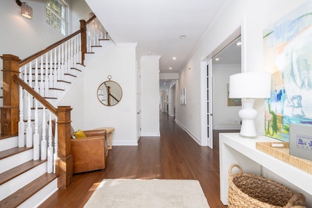 Step into your elegant entryway with gleaming hardwood floors, cozy leather seating, and French doors opening to your private outdoor space.