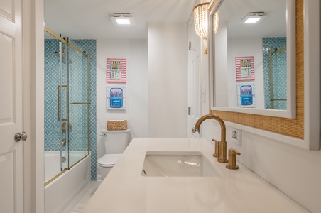 Unwind in your stylish bathroom featuring stunning turquoise tile shower, brass fixtures, and thoughtful touches that create a spa-like retreat.