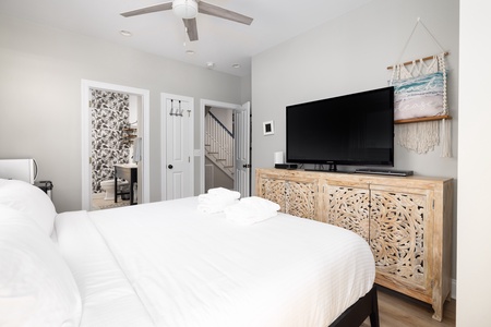 Rest peacefully in this serene bedroom where crisp white linens meet coastal charm, complete with entertainment and thoughtful design touches.