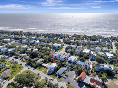 Coastal community with beachfront homes nestled among mature trees, just steps from pristine sandy shores and sparkling ocean waters.