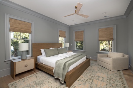 Relax in your serene bedroom featuring a plush king bed, cozy reading chair, and natural bamboo shades filtering gentle light.