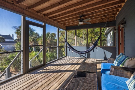 Relax on the spacious screened porch featuring a hammock, ceiling fan, and serene views of lush coastal greenery — the ultimate Lowcountry lounge spot.