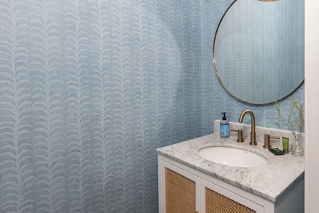 Refresh in your stylish powder room with elegant patterned wallpaper and vanity.