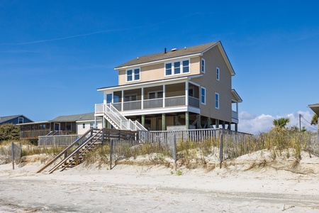Elevated beachfront home with direct beach access via private wooden walkway and stairs.