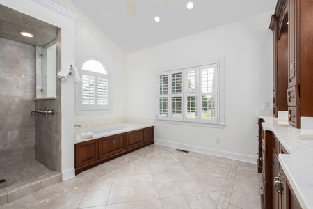 Unwind in your private spa-like bathroom, where elegant dark wood cabinetry meets gleaming marble surfaces. The spacious walk-in shower and soaking tub offer luxurious relaxation after your daily adventures.