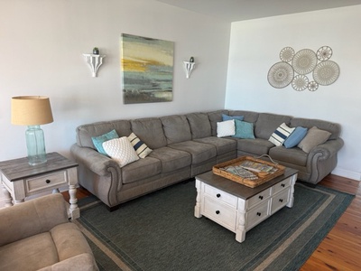 Settle into your spacious living room where a generous sectional sofa invites you to unwind with coastal-inspired décor and warm lighting.