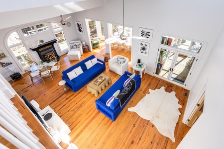 Sunlight pours through soaring windows into your bright, airy living room. Relax on vibrant blue sofas, warm wood floors underfoot, and enjoy the fireplace glow on cooler evenings.