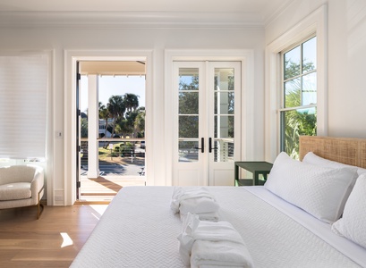 Your bright bedroom opens to a private balcony with tropical views, where crisp linens and natural light create the perfect coastal retreat.