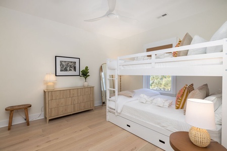 Your kids will love this bright bunk room with cozy linens, storage drawers, and peaceful garden views through the window.