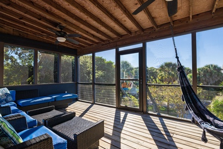 Relax on the screened porch surrounded by lush island greenery — perfect for enjoying the coastal breeze without the bugs.