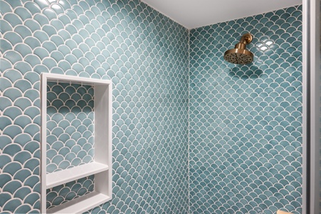 Step into your spa-like shower with stunning sea-green fish scale tiles and elegant brass fixtures for a refreshing retreat.