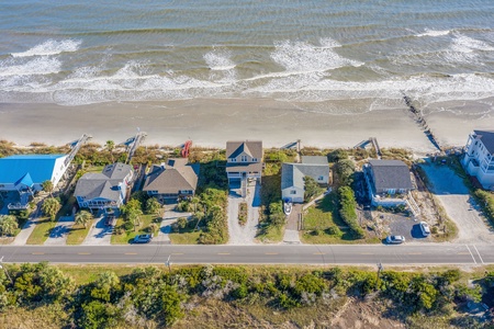 Aerial view of beachfront properties with direct ocean access and private beach walkways along the pristine coastline.