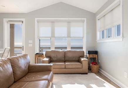 Relax in your bright living room with ocean views through expansive windows and comfortable leather seating.
