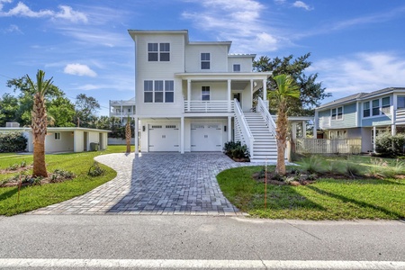 Modern coastal home with tropical landscaping and spacious parking in a peaceful residential neighborhood.