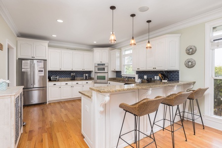 Spacious coastal kitchen at High Tide featuring a large island with seating, perfect for casual dining after a day on the beach.