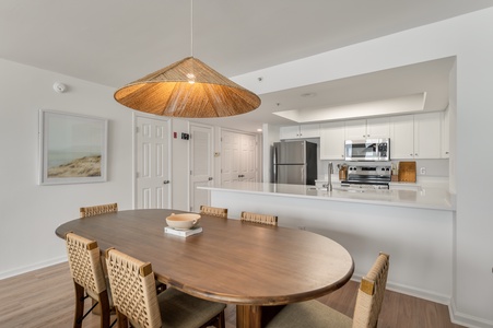 Gather around this elegant dining table where memories unfold under warm pendant lighting, perfectly positioned beside your fully equipped modern kitchen.