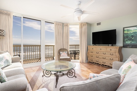 Relax in your coastal living room with panoramic ocean views through floor-to-ceiling windows and step onto your private balcony.