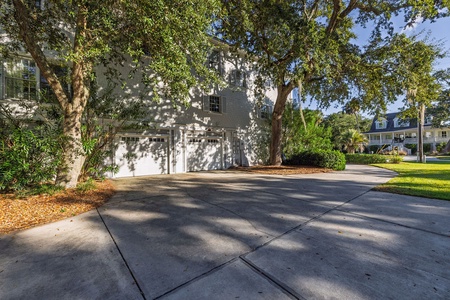 Spacious driveway provides convenient parking beneath mature oak trees.