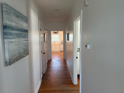 Stroll down your welcoming hallway where warm hardwood floors guide you to the bright, inviting kitchen ahead.