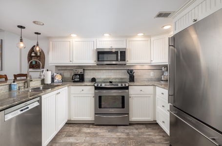 Your fully equipped kitchen features granite countertops, stainless steel appliances, and warm pendant lighting—perfect for preparing meals together.