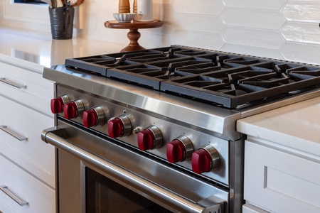 Cook memorable meals on this professional-grade gas range with sleek red controls and spacious burners in your stylish kitchen.