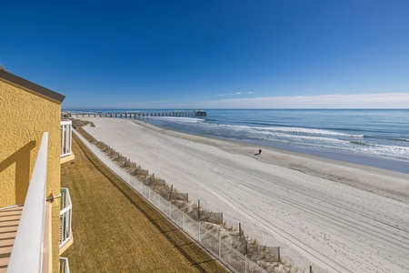 Stunning beachfront property with direct access to pristine sandy shores and iconic fishing pier stretching into sparkling blue waters.