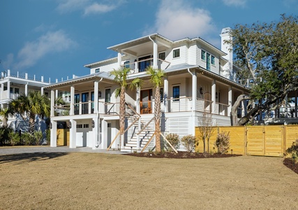 Modern beach house with elevated design, palm trees, and spacious outdoor areas for the perfect coastal getaway.