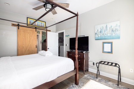 Rest in your elegant four-poster bed with crisp white linens, modern amenities, and stylish city artwork adorning the walls.