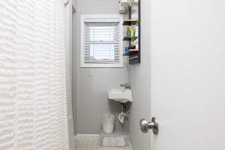 Fresh and bright, your private half-bath features a compact sink, natural light from a frosted window, and crisp white tile accents for effortless convenience.