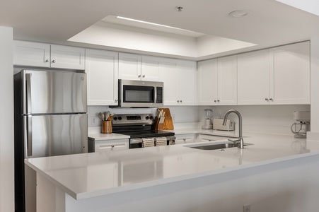 Your modern kitchen features sleek white cabinets, stainless steel appliances, and gleaming quartz countertops perfect for preparing meals.