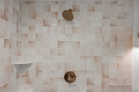 Step into your private shower featuring elegant tiled walls and a rainfall showerhead for your perfect morning routine.
