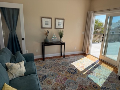 Sink into this bright living room where sunshine streams through patio doors, illuminating your coastal retreat with ocean breezes nearby.