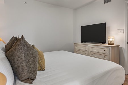 Sink into crisp white linens and plush pillows while your favorite shows play on the flat-screen TV in this serene bedroom retreat.