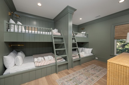 Cozy into your own built-in bunk bed sanctuary with soft linens and privacy rails in this charming sage-green bedroom.