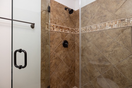 Refresh in this beautifully tiled walk-in shower featuring oil-rubbed bronze fixtures and elegant mosaic accent detailing. Your personal oasis awaits.