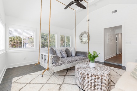 Unwind in your chic sitting room, featuring a cozy rope swing and large windows for natural light